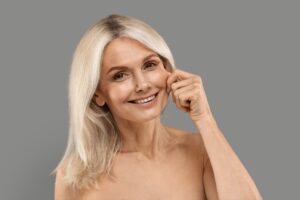 Cheekbone Augmentation. Beautiful Mature Woman Touching Cheek And Smiling At Camera