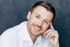 Cheerful male employee has joyful expression, keeps finger on temple, rejoices starting vacation.